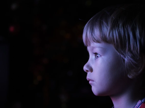 Close-up of little boy whose face is lit by a TV screen