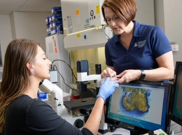 Limesand and a team member look at a petri dish with a radiology scan on a monitor.
